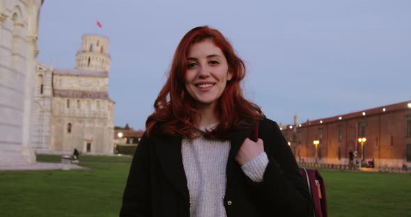 Young University Girl with Backpack in an Italian Square Smiles at the Camera