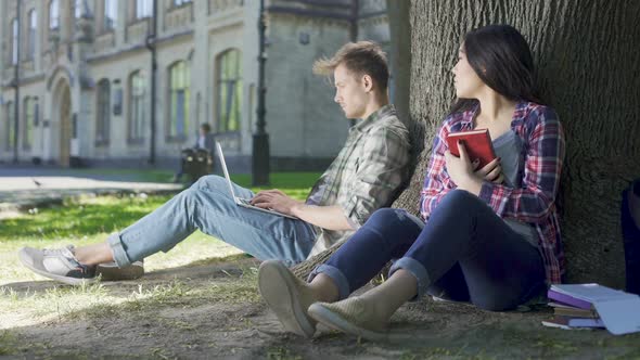 Multinational Girl Sitting Under Tree, Holding Book, Looking at Guy, Feelings