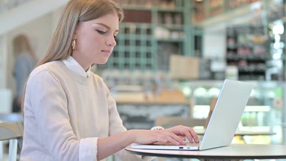 Thumbs Up By Young Woman Using Laptop in Cafe