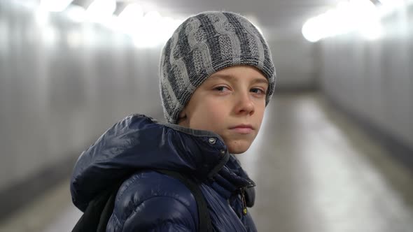 Portrait of Alone Confident Boy in Hat and Jacket in Underground Covered Walkway in City at Winter