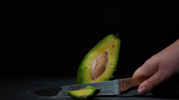 Closeup Female Hand Cutting Green Avocado with Knife in Slow Motion Leaving