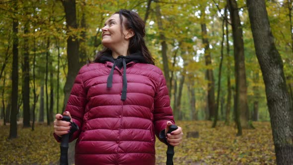 Panning Shot of Happy Mature Caucasian Woman Smiling Admiring Beauty of Autumn Nature in Forest