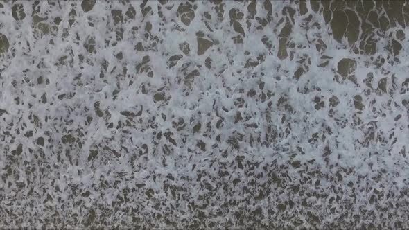 Top down shot of waves crashing onto the beach of Scheveningen in the Netherlands. This is the North