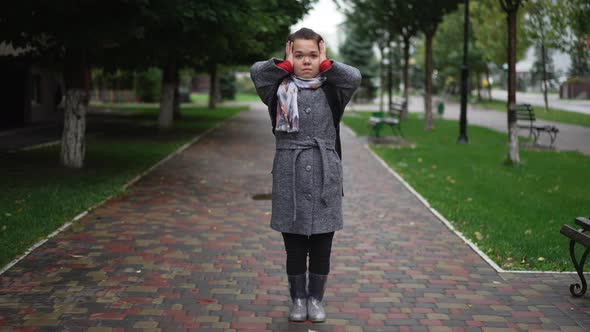 Wide Shot Portrait of Troubled Stressed Caucasian Little Woman Closnig Ears Standing on City Street