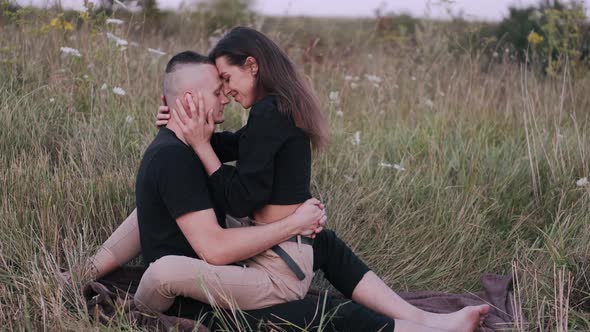 Loving Man and Woman Sitting in Field and Hugging