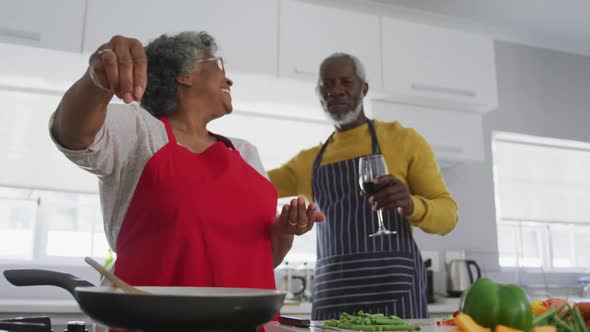 A senior african american couple spending time together at home cooking social distancing in quaran