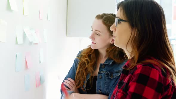 Female executives discussing over sticky notes