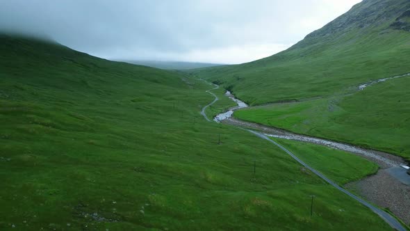 Drone shot revealing green country road under mountain