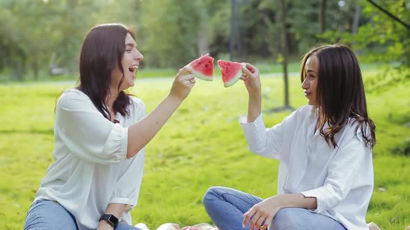 Close-up View of Two Beautiful Best Girlfriends Having Fun, Playing with Slices of Watermelon