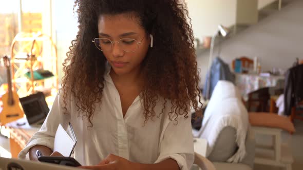 Serious black businesswoman using smartphone at home