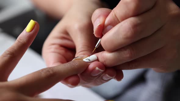 Anonymous beautician applying lacquer on female client nails