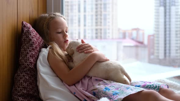 Little Girl Petting Labrador Puppy on Windowsill