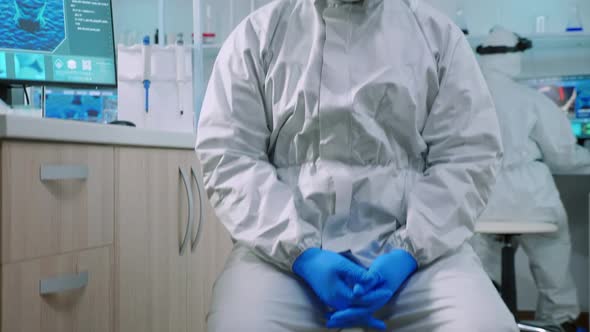Doctor Man Looking at Camera Sitting in Lab Dressed in Ppe Suit