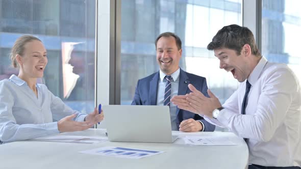 Business People Celebrating Success and Using Laptop