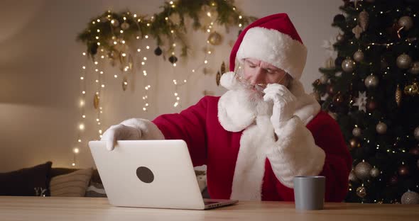 Kind Elderly Santa Claus Taking Off His Glasses After Long Online Work at Home Close the Laptop Lid