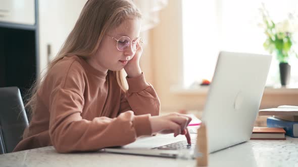 Beautiful 10 Years Old Girl Doing Her Homework Using a Laptop