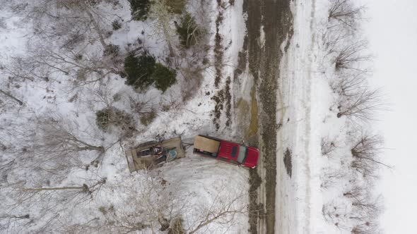 Pickup truck with trailer of snowmobiles reversing and pulling out onto road in Winter snow