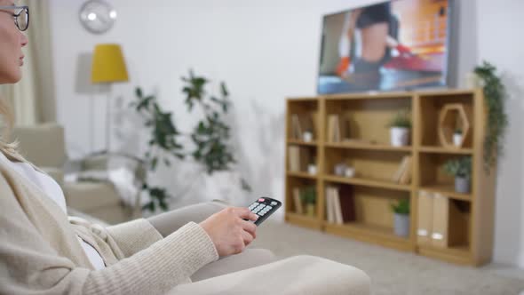 Woman Switching TV Channels with Remote Control