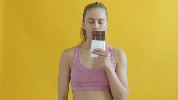 Portait of Young Sportswoman Smelling Chocolate Then Waving Head Saying No Losing Weight