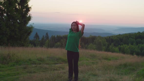 Elegant Lovely Yogi Asian Woman Warming Up Stretching Arm and Neck Muscle Outdoors at Daybreak