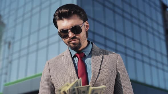 Greedy Rich Man in Stylish Suit Wearing Sunglasses Counting Money and Looking To Camera in the