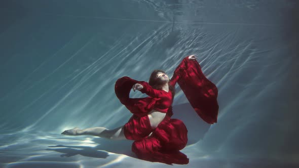 Attractive Young Woman Swims Beautifully Underwater in a Red Dress