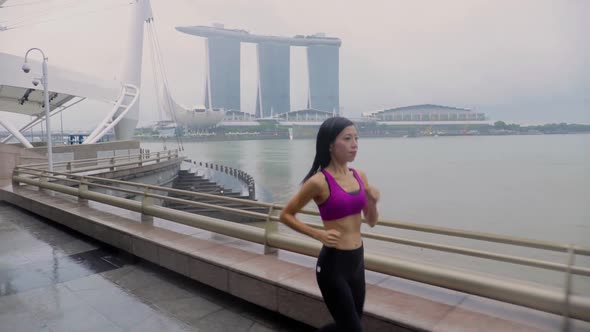 Middle-aged Asian woman jogging in the rain in Singapore 