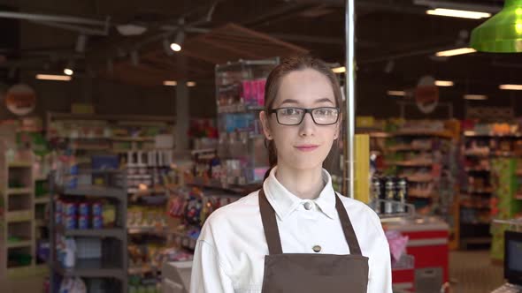 The Girl Supermarket Cashier Smiles for the Camera