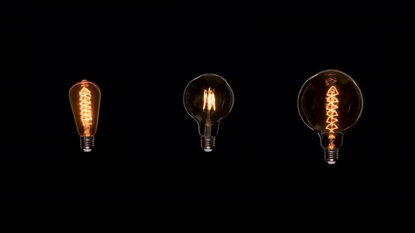 Three Edison Dirty Bulbs with Dust Inside Glass Flicker on Black Background. Amber Tungsten Color