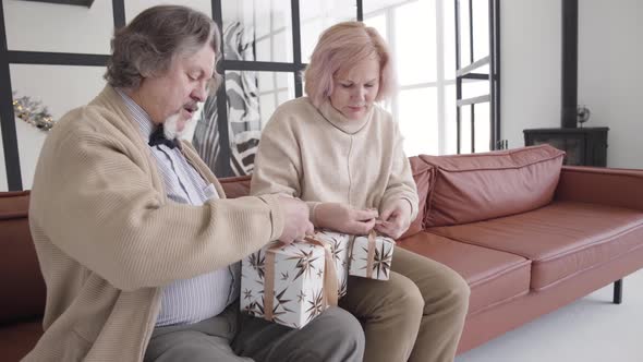 Senior Caucasian Man and Woman Packing Christmas Gifts at Home. Portrait of Positive Male and Female