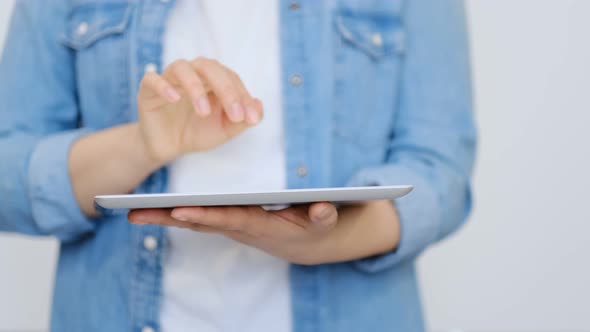 Close Up on the Hand of Young Handsome Woman Pointing and Touching the Screen of a Tablet with Her