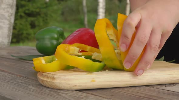 The Woman Cuts a Yellow Pepper on the Large Round Pieces