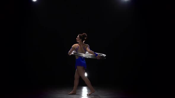 Gymnast in a Bright Outfit Twists a Hoop on Her Arm and Then on Her Leg