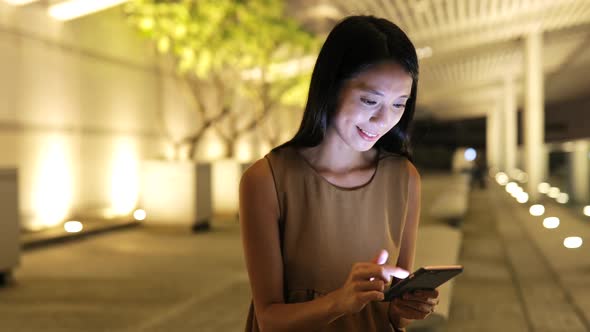 Woman looking at mobile phone in city at night 