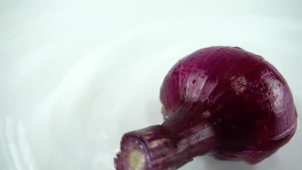 Rotating blue onion in water on a white background. Slow motion.