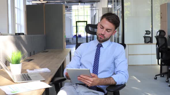 Businessman working on using tablet sitting at the desk. Busy young entepreneur at modern office