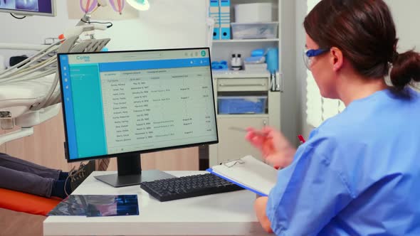 Orthodontist Nurse Looking at List with Appointments Taking Notes