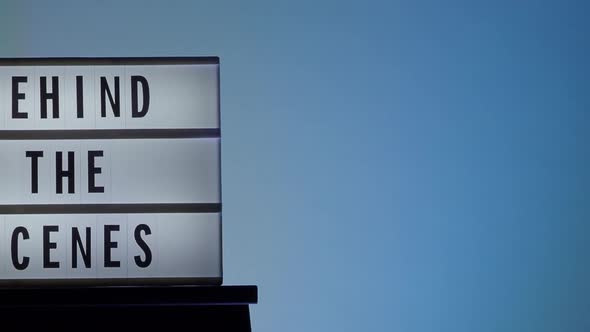 Behind the scene letters on cinema light box. Black text on white LED lightbox of word Behind the