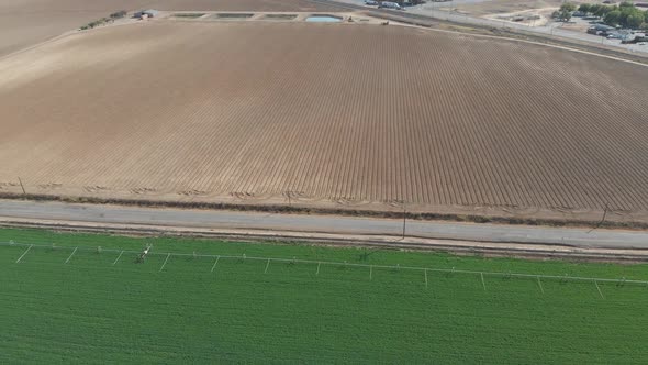 Aerial of a perfectly green Southern California vegetable field, with irrigation equipment.  A neigh