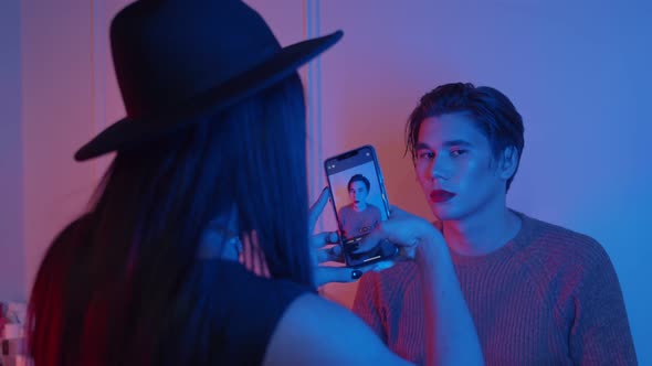 Makeup Studio - Woman Artist Taking Photo of Her Male Model with Makeup on in Neon Lighting - Bold