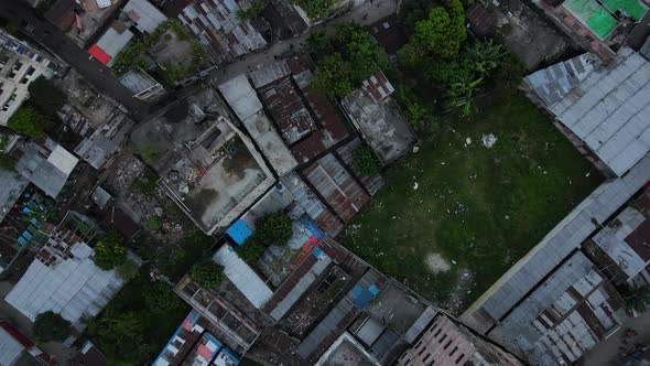 Top down aerial slum area with city buildings and little green space - drone ascending shot