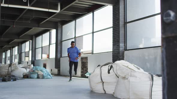 African american man wearing sports clothing jogging through an empty urban building