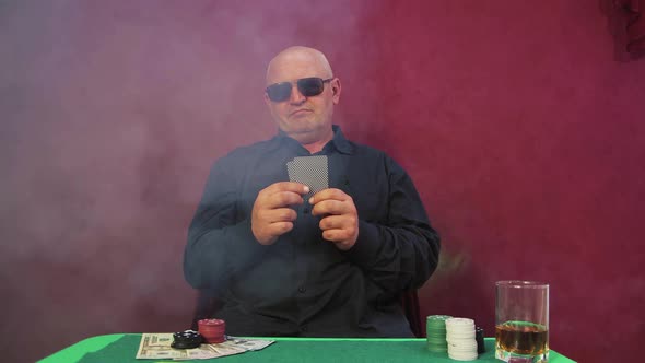 The Risky Gambler in the Casino Looks and Folds His Cards