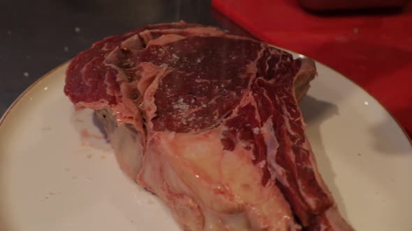 Raw Piece of Juicy Ribeye Meat Stake Putting Salt and Pepper Before Cooking