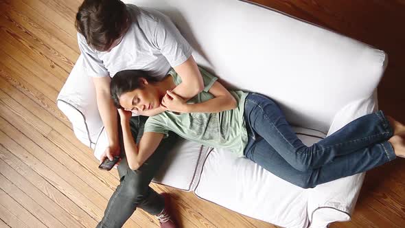 Woman napping on sofa with head resting on boyfriends lap