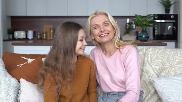 Happy Middle Aged Mom Hugging Cute Teen Child Daughter Sitting on Couch