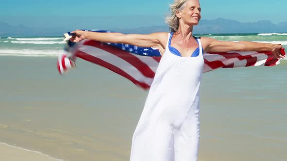 Senior woman with american flag at the beach