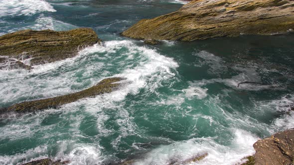 Sea wave rolling through ocean rocks crashing on shore