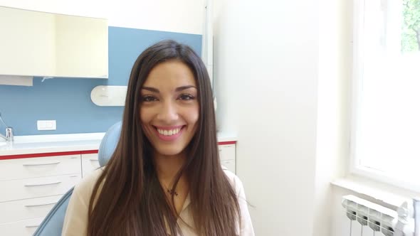 Close up of smiling woman looking at camera while sitting in the dental chair