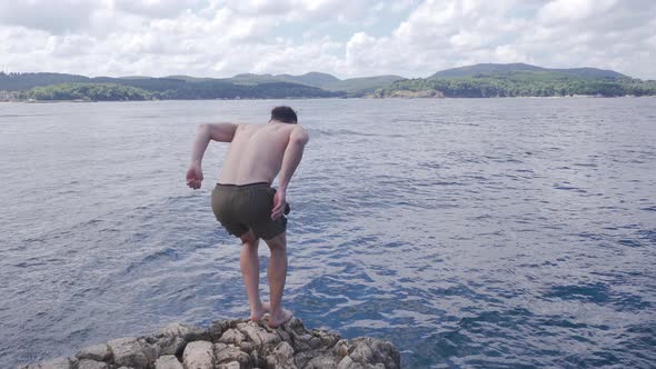 The man running from the rocks and jumping into the sea.